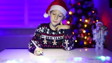 Noel ışıklarının arkasındaki bir çocuk Noel Baba 'ya mektup yazıyor.
