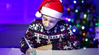 Noel ışıklarının arkasındaki bir çocuk Noel Baba 'ya mektup yazıyor.