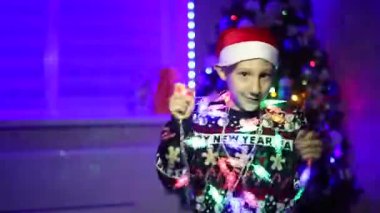 Noel Baba şapkalı bir çocuk yeni yıl arkaplanda çelenklerle dans ediyor.