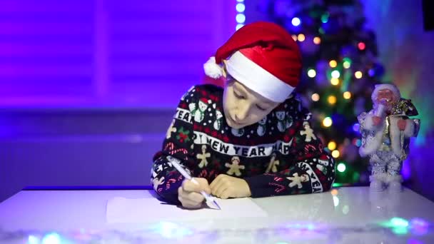 Мальчик Фоне Рождественской Елки Пишет Письмо Санта Клаусу — стоковое видео