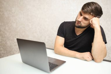 Bir adam dizüstü bilgisayarın önünde oturuyor.