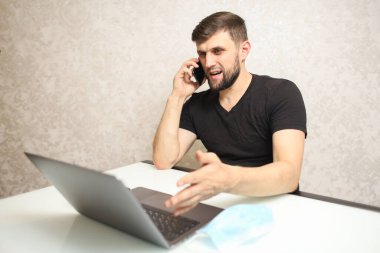 Kendini izole eden bir insan evde çalışır ve telefonda konuşur.