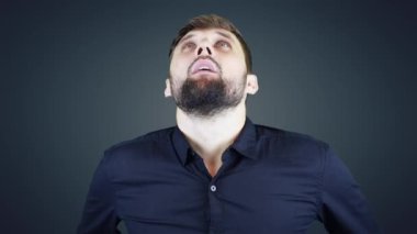 Kameraya poz veren koyu renkli gömlekli bir adam.