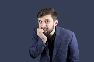 Mavi takım elbiseli bir işadamı korkudan tırnaklarını yiyor.