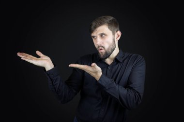 Siyah gömlekli ve siyah arka planlı bir adam avuç içlerinin hareketlerini gösterir.