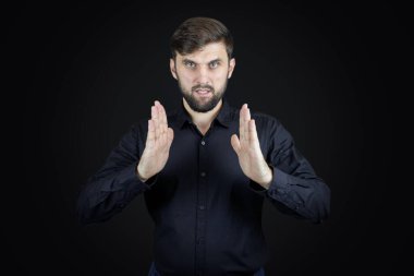 Siyah gömlekli ve siyah arka planlı bir adam avuç içlerinin hareketlerini gösterir.