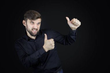 Siyah gömlekli ve siyah arkaplanlı bir adam onaylıyor.