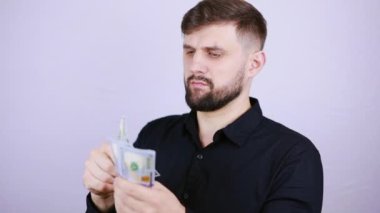 Erkek bir işadamı kenarda durur ve dolarları sayar.