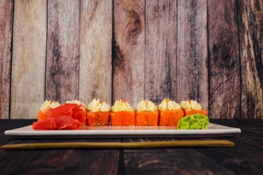 Ahşap masada wasabi peyniri ve zencefilli suşi ruloları.