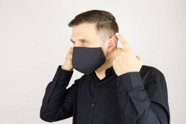 Bir adam siyah bir tıbbi maske takar.