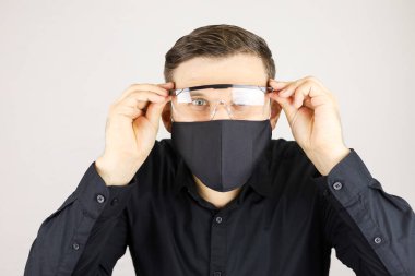 Siyah gömlekli adam tıbbi gözlük takıyordu.