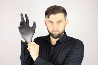 Adam siyah bir tıbbi eldiven takıyor.