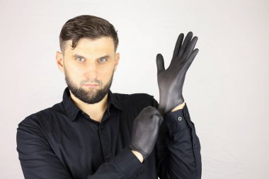 Adam siyah bir tıbbi eldiven takıyor.