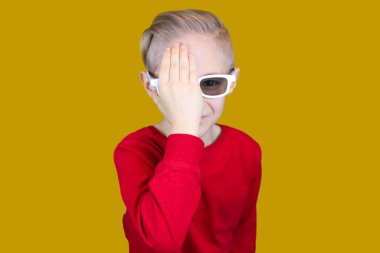 Üç boyutlu gözlüklü bir çocuk elleriyle gözlerini kapadı.