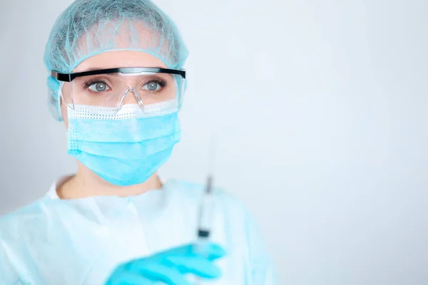 顔に透明な眼鏡をかけた医療用ガウン マスク 保護手袋の看護師は注射用注射器の針を見て — ストック写真