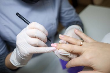 Manikür ustası tırnaklarına jöle sürmek için parmaklarını tutuyor.