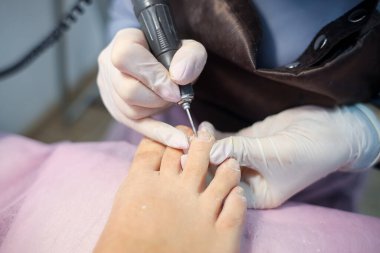 Pedikür ustası müşterinin ayak tırnaklarının derisini hazırlar.