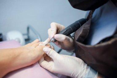 Pedikürcü, müşterinin ayağıyla birlikte tırnak cilası kaplama prosedürünü hazırlar.