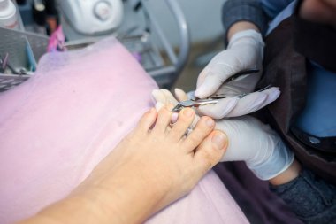 Kız pedikür ustası profesyonel çivi aletleriyle çalışır.