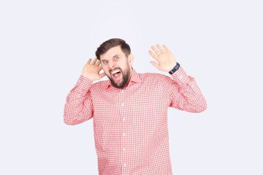 Adam ellerini kaldırdı. Beyaz arka planda pembe tişörtlü sakallı bir adam.