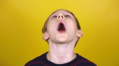 Çocuk ağzını açar ve esner. Çocuk sarı arka planda çeşitli duygular sergiliyor..