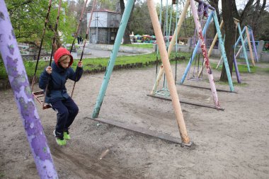 Bir çocuk demir bir salıncakta sallanıyor.