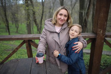 Anne ve oğul kucaklaşır bir kafede oturup kahve içerler.