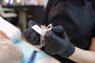 Dövme sanatçısı kalıcı makyaj prosedürü için tek kullanımlık kartuşların paketlerini yırtarak açar.