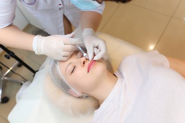 Kozmetik uzmanı dudağın üst kısmına hiyalüronik asit enjekte ederek müşterinin dudaklarının hacmini arttırır.