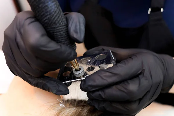 permanent makeup artist installs tattoo pigment in tattoo machine