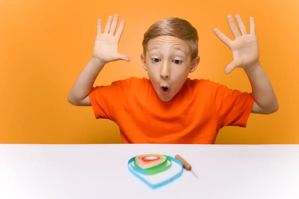 Een Jongen Een Oranje Shirt Zit Aan Een Witte Tafel — Stockfoto