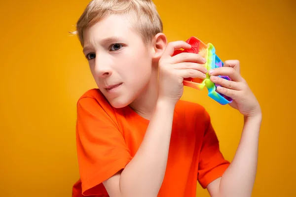 Chłopiec Trzyma Silikonową Zabawkę Antystresową Przed Nim Próbuje Pop Piłki — Zdjęcie stockowe