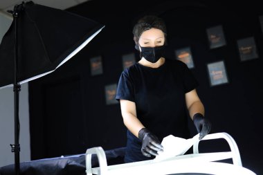 Dövmeci işyerinin önünde duruyor ve onu dezenfektanla dezenfekte ediyor.