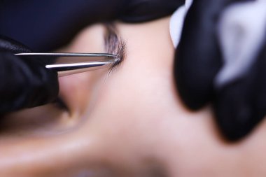 Usta dövme sanatçısı, kaşlarını fazla kılları yolmak için hazırlar. Kaşların dış hatlarını dövme için hazırlar.