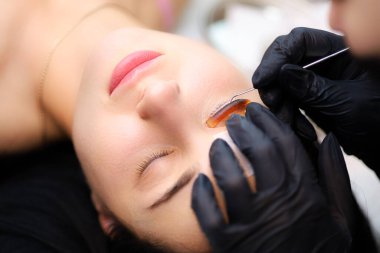 Cilanın kaplamasının ustası, kirpiklere özel bir alet yapıştırılarak kaplama için bileşimler uygular.