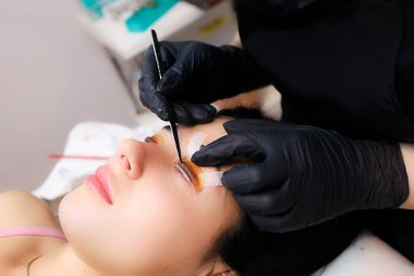 müşteri üzerine eğilmiş silia kaplama ustası ve halihazırda bukle rulo yapıştırıcı yapıştırılmış silia hizalama yapar