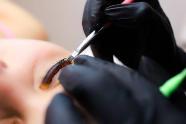 Ustanın ellerine yakın çekim yap ve fırçayla kirpiklerine boya sür. Zaten kıvrım için rulo yapış yapış.