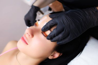 Kirpik kaplama ustaları müşterinin göz kapaklarına kirpikleri kıvırmak ve daha fazla kaplama yapmak için yapıştırılmış.