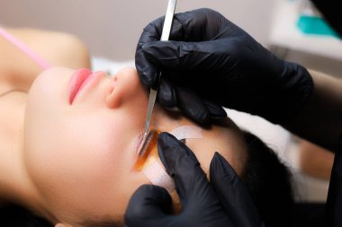 müşteri üzerine eğilmiş silia kaplama ustası ve halihazırda bukle rulo yapıştırıcı yapıştırılmış silia hizalama yapar