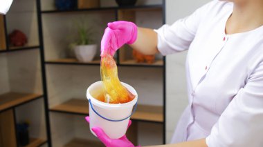 Şekerden kıl kesme ustasının yakın plan çekimi önünde bir kova şeker tutuyordu, elinde sıkıştı ve bu kovanın üzerine kaldırıldı, tutkal bu elden akıyor.