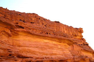 Çöldeki bir kanyonun kırmızı kayaları mavi gökyüzü manzarasına karşı aşağıdan yukarıya
