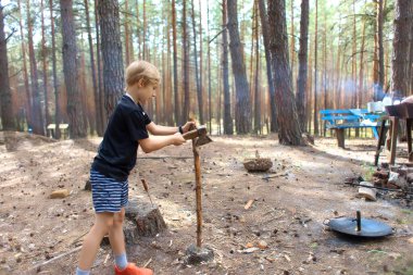 Turist kampındaki bir çocuk ateş yakmak için odun hazırlıyor.