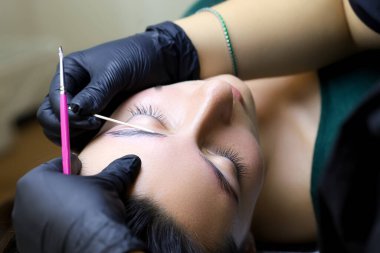 Kaşların laminasyonu siyah eldivenli usta profosyonel lamasyon için uygulanan bileşimi düzeltir.