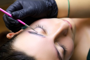 Kaşların laminasyonu siyah eldivenli usta profosyonel lamasyon için uygulanan bileşimi düzeltir.