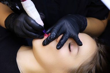 Modelin dudaklarında dövme makinesi olan pigmentin tekrarlanan uygulaması