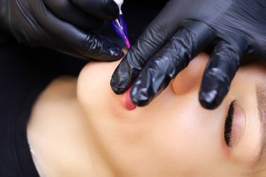 Dövme sanatçısı, sonucu pekiştirmek için pigmenti modelin dudaklarına tekrar tekrar uygular.