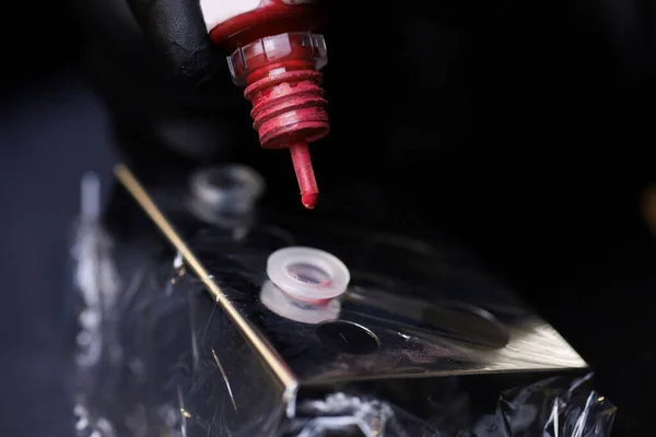 Dövme pigmentlerini karıştırmak için ana pigmentleri kavanozdan plastik kapsüle damlatan yakın plan.