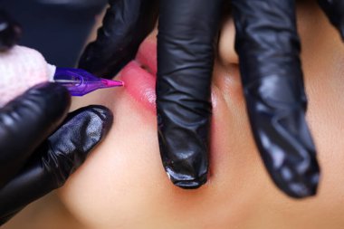 Dövme sanatçısı, sonucu pekiştirmek için pigmenti modelin dudaklarına tekrar tekrar uygular.