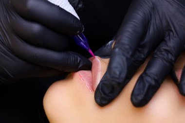 Dövme makinesinin burnuna ve iğnesine yakın çekim dudakların çevresi boyunca dövme yapar.