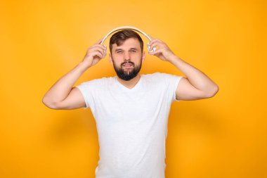 Sakallı adam kulaklığını takıyor.